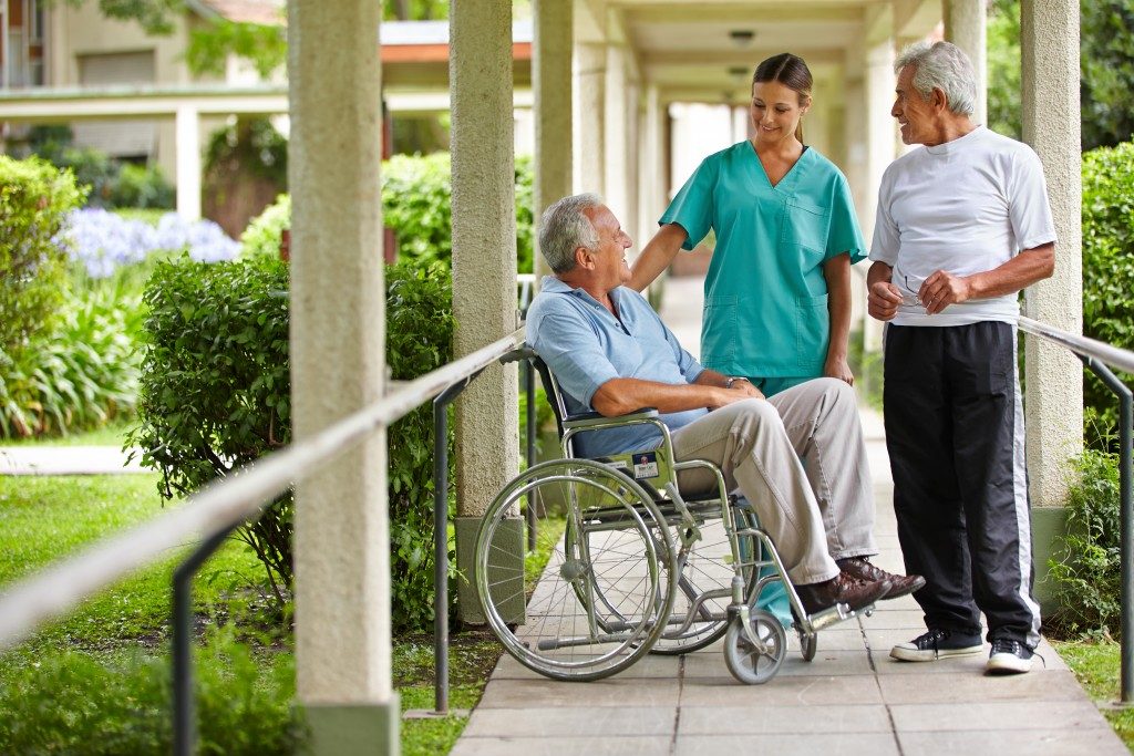 Two elderly men talking to a nurse