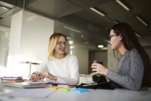 two woman talking in the library