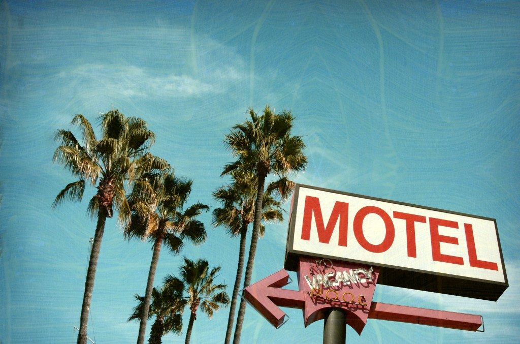 aged and worn vintage photo of motel sign palm trees