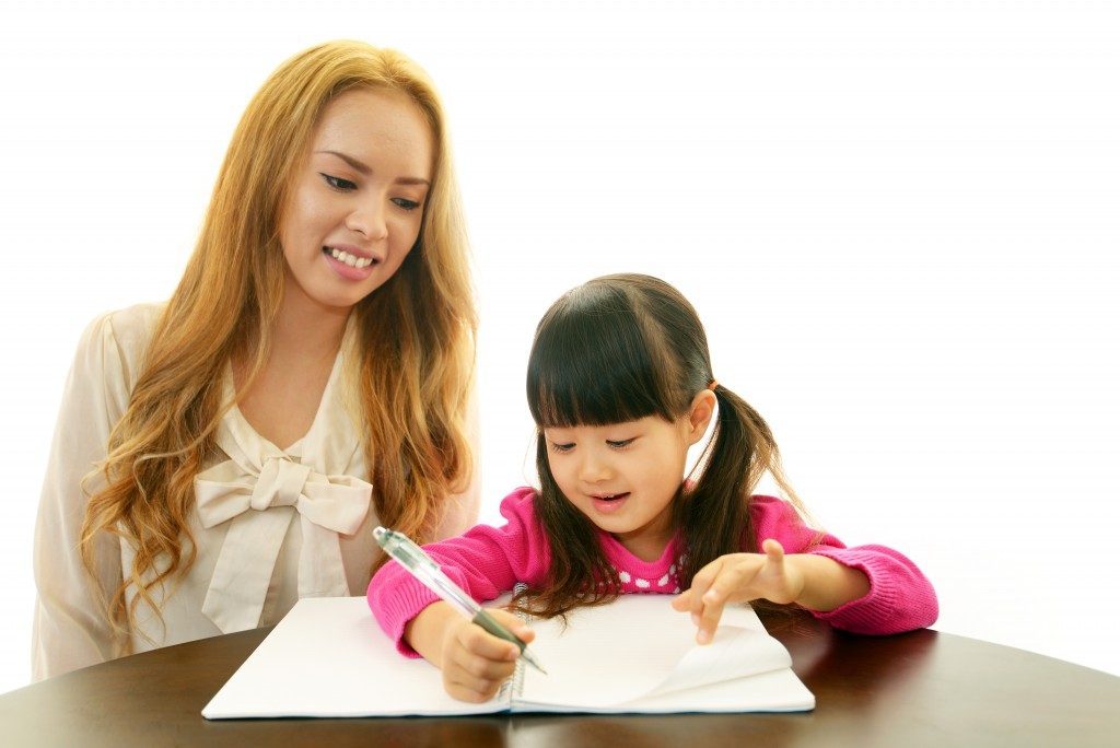 Little girl studying with her mom